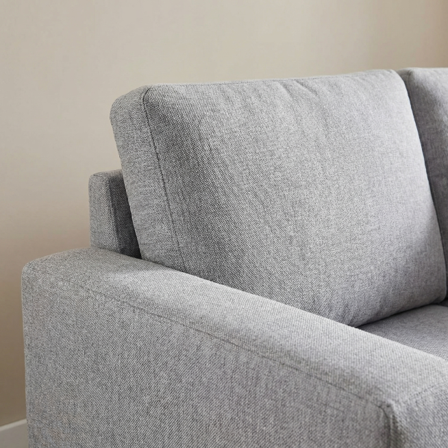 特写浅灰色布艺L型转角沙发的面料细节，保留浅灰色纹理布艺的材质特征，展示细腻的织物质感，保持产品材质特征不变。放置在简洁的浅色背景上，柔和侧光突出布料纹理肌理。商业细节摄影，超清画质，对焦清晰，突出材预览效果