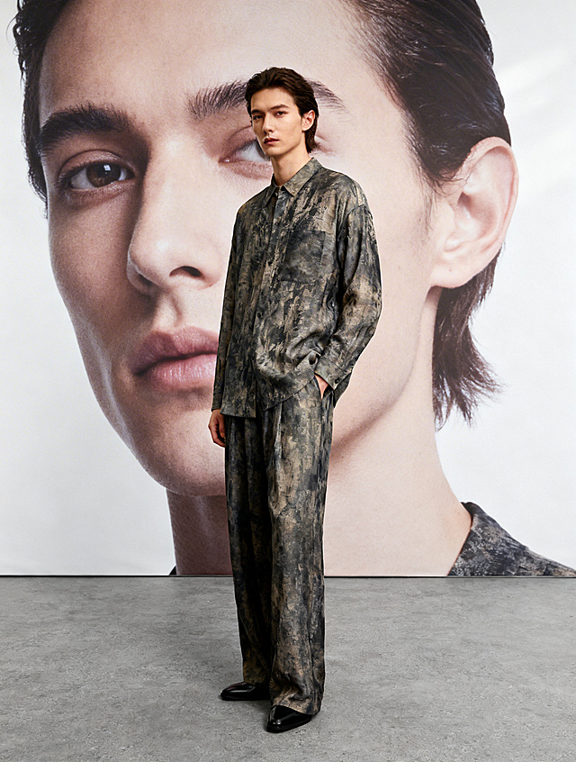 现代简约风格，融合时尚与商务感，抽象面料纹理彰显质感，人物与巨幅肖像呼应，营造潮流视觉张力。