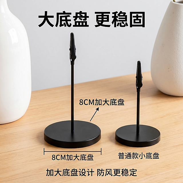 [主图-2] 8CM大底盘防风稳定性卖点展示图。
[氛围风格] 家居治愈风，温馨简约酒店氛围；
[画质] 商业摄影质感、光线柔和通透、产品清晰真实、画面干净高级。
[元素] 侧放展示支架底盘，特写放大8CM圆形大底盘，标注8CM尺寸，旁边放置常规款小底盘做大小对比，背景是干净浅原木桌面，浅灰色墙面。保持产品外观（即物理结构、材质质感、颜色）与输入产品图绝对一致，杜绝任何变形和色差，精细化处理。商品主体占比严格控制在70%左右；画面满屏无边框。
[光影] 柔和均匀自然光，侧光突出底盘厚度和金属质感，明暗清晰，过渡自然。
[配色] 主色调浅木色+浅灰+金属银，清新治愈，大尺寸对比清晰。
[视角构图] 平视特写视角，主体底盘居中，对比清晰，景深适中。
[文字版式] 顶部大字标题"大底盘 更稳固"，黑色粗体居中；左侧引线标注"8CM加大底盘"，对应大底盘位置；右侧对比标注"普通款小底盘"。底部小字说明"加大底盘设计 防风更稳定"居中排列，清晰易读。
[比例分辨率] 1:1比例，2k分辨率；文字清晰锐利，画面超高清。
[负向提示词] 变形，水印，文字错乱，产品图模糊，背景杂乱。