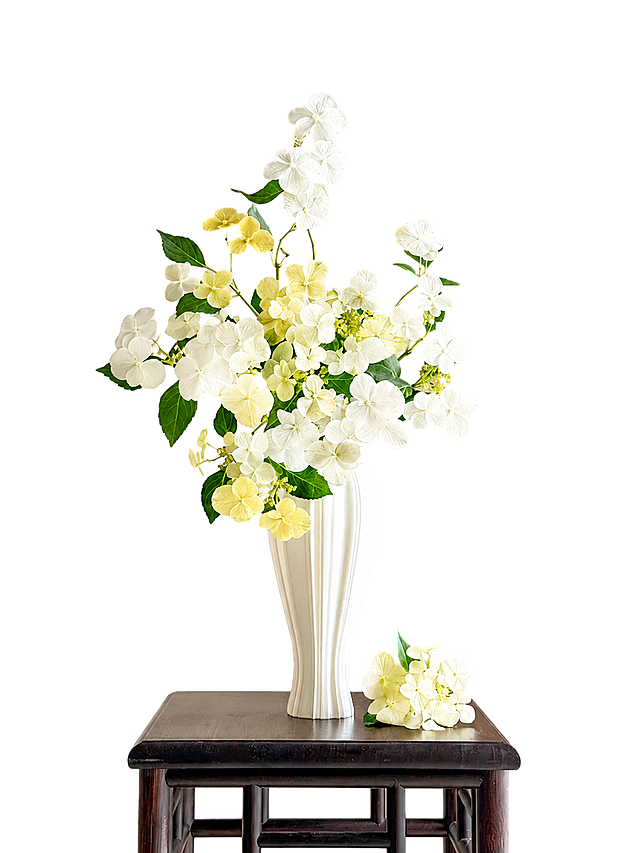 将图中所有紫蓝色绣球花替换为白色和黄色花朵，保持花瓶、绿叶、桌子和背景不变