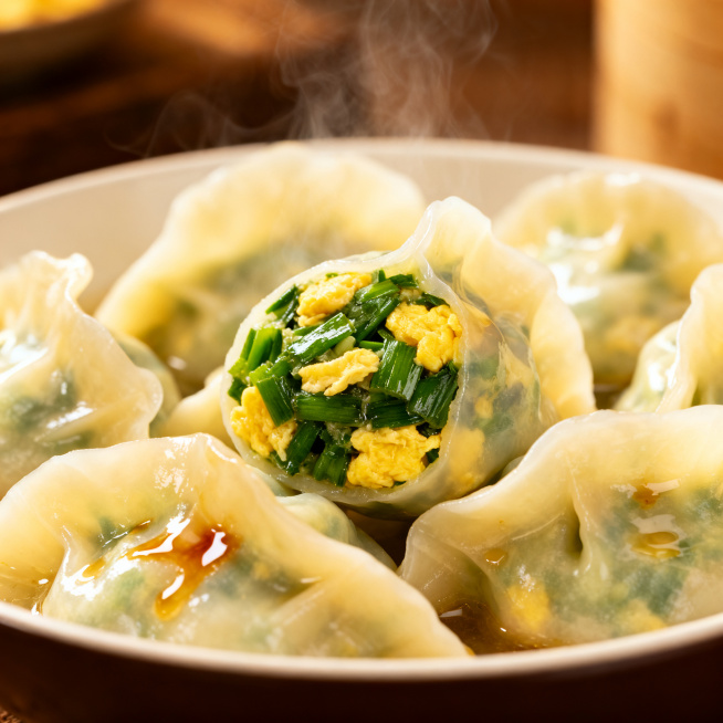 生成喜福记韭菜鸡蛋水饺场景图，展示水饺煮好后的诱人成品，翠绿韭菜搭配金黄鸡蛋，汤汁饱满，体现皮薄馅鲜的特点，适合电商展示预览效果