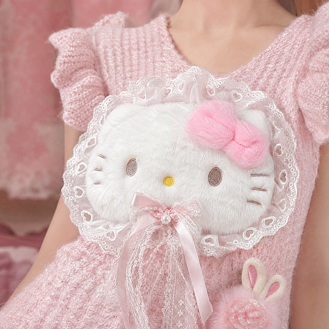 [主图-4] 细节特写展示，突出Hello Kitty公仔、蕾丝花边和毛球兔耳等精致细节。
[统一基调] 甜美少女风 软萌氛围感 高清实拍质感 粉色系柔和色调 自然光效。
[画面] 模特上半身近景特写，聚焦展示粉色Hello Kitty毛绒蕾丝针织吊带背心的胸前细节。清晰展示白色毛绒Hello Kitty公仔的蓬松质感、粉色蝴蝶结的柔软形态、蕾丝爱心花边的精致纹理、粉色缎带蝴蝶结和珍珠吊坠的光泽。画面中同时可以看到肩部小飞袖的针织纹理和下摆一侧的粉色毛球兔耳装饰。模特只露出下巴和颈部以下，重点突出衣服细节。背景虚化，为同系列粉色柔和背景，让细节更加突出。
[光影质感] 柔和近摄光，毛绒质感蓬松真实，蕾丝花边细腻通透，针织面料纹理清晰可见，珍珠有自然光泽，整体质感高级。
[配色] 主色调粉色、白色，色彩柔和饱满，细节处色彩层次丰富。
[文字版式] 无文字，纯图展示。
[输出要求] 比例1:1，细节清晰锐利，质感真实，无变形、无水印、无平台Logo、无模糊。