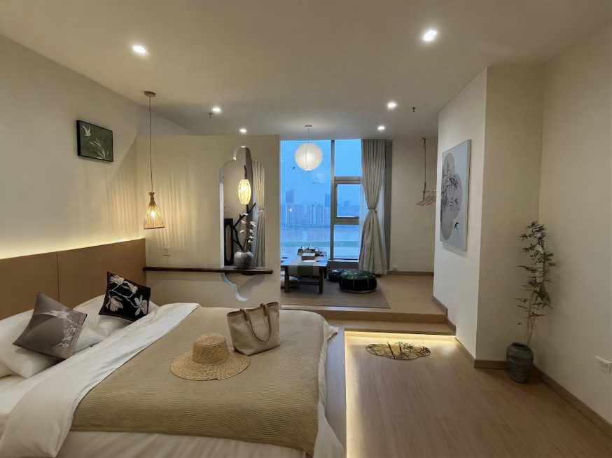 在床靠近枕头的位置放置一顶草编宽檐草帽和一个米色帆布手提包，摆放自然合理，风格符合新中式禅意调性。保持原图整体新中式江景民宿结构、光影、江景和其他所有物品不变。光影匹配：原图光源来自顶面筒灯和吊灯，在预览效果