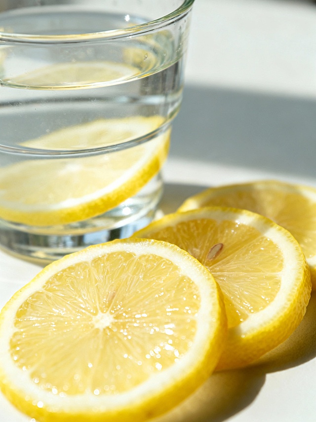 透明水杯旁摆着几片新鲜柠檬