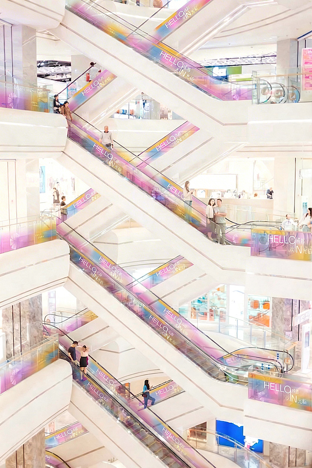 去掉图片左上角的“金鹰世界”水印logo，保留背景颜色和整体画面不变，保持商场扶梯场景、人物和其他贴纸完整，光影和原图保持一致