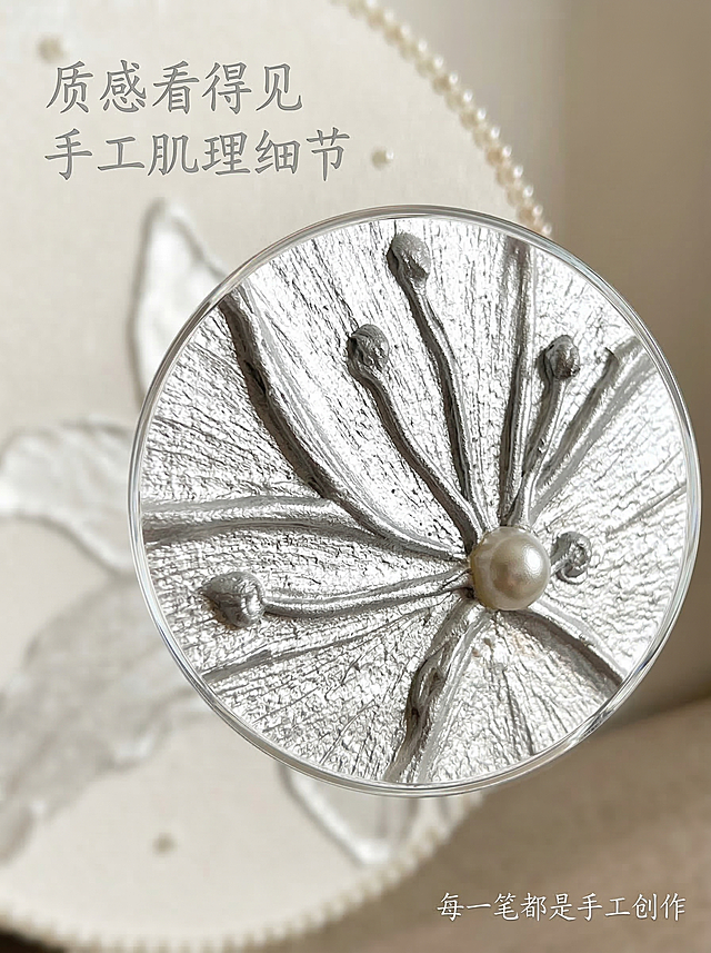 [垫图]
[主图主题] 局部肌理细节放大装饰画
[氛围/风格] 高级温柔轻简奢华 微距质感
[画面元素] 使用放大镜放大效果，聚焦展示百合花瓣边缘的手绘肌理，凹凸的笔触纹理清晰可见，珍珠光泽在光线下的反光效果自然突出，强调整体工艺细节和质感，背景为浅奶白色虚化处理，突出主体细节，背景铺满全屏
[配色色系] 主色调：奶白银灰；辅助色：珍珠米白
[视角构图] 微距特写 中心构图
[文字版式] 主标题 “ 质感看得见 
 手工肌理细节 ” 悬浮在画面左上角，字体为纤细手写体，银灰色，右下角标注副标题 “ 每一笔都是手工创作 ”，不遮挡核心细节，排版干净高级。