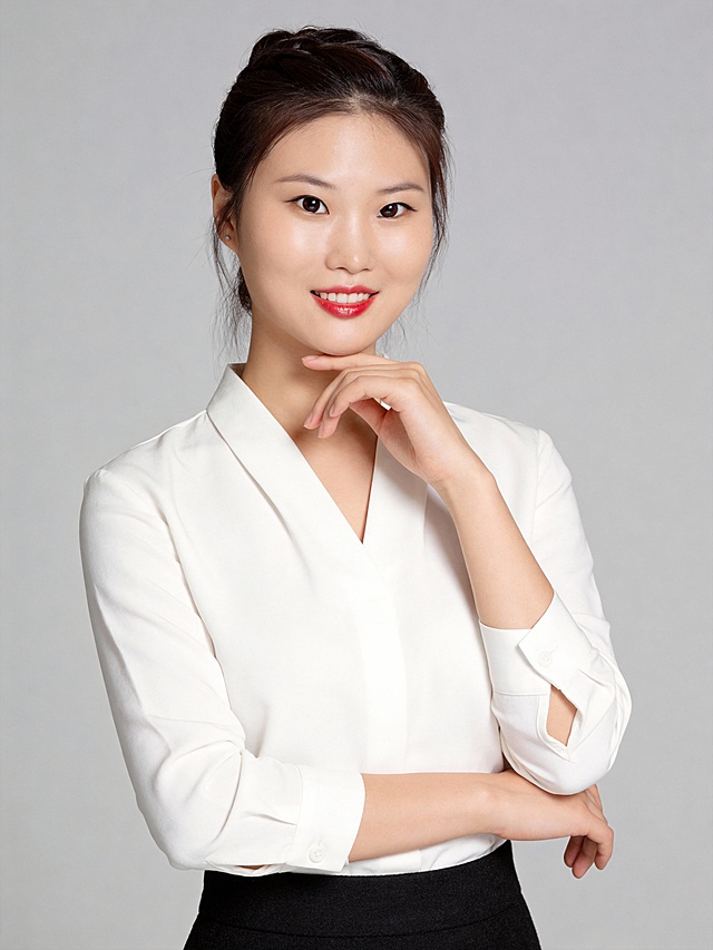 参考第一张图保留人物脸型､年龄等特征生成职场形象照,参考第二张图人物占位和比例,标准焦段50mm,F/4光圈(F/2.8-F/4区间),平视视角(镜头与人物视线齐平);人物占画面70%,人物居中(居中构图),位于画面中心,为视觉聚焦点,入境范围头部及以下至臀部下方10cm(半身像);左右留少量背景空间;头部与画面顶部保留5%空间;头部发型完整;原生肤质白皙细腻(通透自然),韩式精致浓妆(整洁清透通勤妆容)冷调玻璃肌通透底妆,肤质细腻,冷调白皙,极淡裸粉哑光眼影打底,极细内眼线填充睫毛根部,大直径深棕色带细微高光点的自然款美瞳;边缘模糊无生硬轮廓;唇妆:粉调草莓红镜面水光唇釉,唇形饱满､唇峰清晰､唇面透亮光泽,唇周无晕染;腮红:淡粉色氛围感腮红轻扫苹果肌内侧,无明显妆感;身着净白色V领韩式长袖衬衫(优选细腻棉质面料,自带柔和垂坠感,V领弧度修饰颈部线条,袖口微收利落不拖沓);下搭高腰黑色哑面羊毛混纺材质包裙(高腰线设计,通勤感)｡发型为韩式精致高束发,鬓角与颈侧几缕轻盈碎发随性柔和灵动;姿态优雅松弛:左手手轻托下颌;右手自然交叉于臂弯,身姿随性有度,自然松弛感站立姿势｡唇角微微浅笑,眼神澄澈灵动温和明亮,看向镜头,自带职场女性的专业与亲和感;画面整体干净清爽,自信从容｡专业棚拍人像写真,柔和自然布光,4800K中性光色温,面部光比精准控制1:1.3,面部光线均匀;主体锐利清晰,背景:极简纯中度灰色背景(光线呈现均匀柔和干净通透质感),严格按照第一张图内容生成。