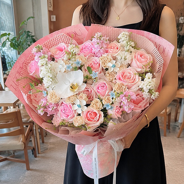 基于图1的花束进行修改：1. 参考图2的白色紫罗兰形态，在花束中添加2支白色紫罗兰间插在花材中，其他原有花材和包装保持不变；2. 更换背景为白天的咖啡店室内场景，有一位美女正面抱着这束花，美女不要露出脸部，只展示身体和花束；3. 背景及花束的亮度稍微调高一点点，不要调太高，保持自然；4. 整体画面自然真实，光影协调，花束质感清晰。