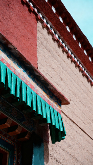 低饱和大地色，自然光，治愈安静，极简高级，藏式质感，无多余搭建，留白充足，电影感，干净通透，传统藏式建筑墙面，朱红松石绿配色，合规悬挂的经幡局部，非遗质感，庄重不浮夸预览效果