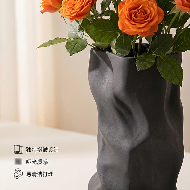 [主图-2] 材质细节卖点展示-褶皱花瓶细节特写
[氛围风格] 简约高级家居治愈风，温馨居家质感
[画质] 商业摄影质感、光线柔和通透、产品清晰真实、画面干净高级
[元素] 深灰色褶皱花瓶的局部特写，重点展示花瓶独特的褶皱肌理和哑光材质表面，花瓶插着少量橙色玫瑰花头和绿叶突出器口设计。保持褶皱花瓶的外观（物理结构、材质质感、颜色）与输入产品图绝对一致，杜绝任何变形和色差，精细化处理。商品主体占比严格控制在60%-80%之间，画面满屏无边框。
[光影] 柔和侧光突出褶皱的凹凸纹理，光影层次分明，哑光材质的高级感呈现自然，明暗过渡柔和
[配色] 主色调：深灰褶皱+橙色玫瑰点缀，背景浅素色调不抢主体
[视角构图] 近距离特写视角，对焦花瓶褶皱肌理，景深较浅突出细节
[文字版式] 左下角排列卖点，图标+短句组合：「独特褶皱设计」「哑光质感」「易清洁打理」，文字简洁，深色字体浅色背景衬托，不遮挡主体细节
[比例分辨率] 1:1比例，2k分辨率，文字清晰锐利，超高清
[负向提示词] 变形，水印，文字错乱，产品图模糊，背景杂乱，文字遮挡主体