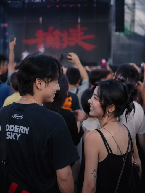 一男一女两个25岁左右的年轻人在摇滚音乐节的人群中相视一笑，人群中只注意到彼此，真实人像质感，自然真实的摄影氛围预览效果