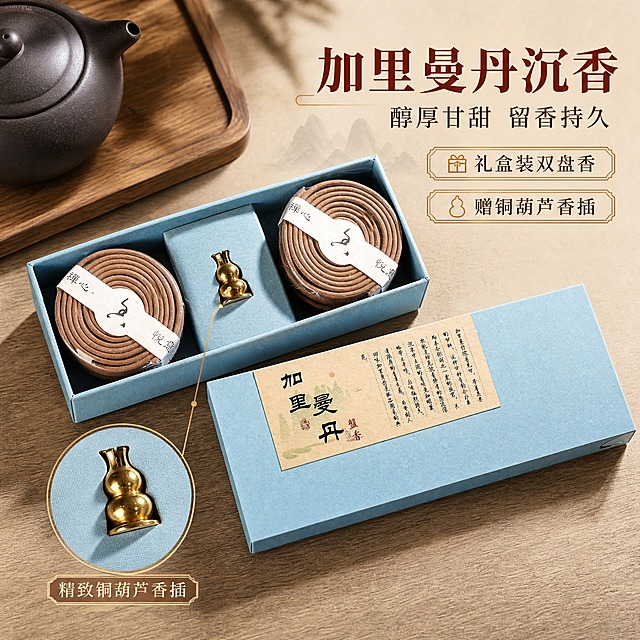 [主图-3] 加里曼丹 盘香礼盒装，主题为蓝盒开箱内景与细节质感展示，突出沉香品质与礼盒配置。
[统一基调] 新中式禅意国风商业摄影风格；背景主色=浅米杏+深木色；标题字色=深赭石色；辅助字色=深棕灰；强调色=暖金色；字体样式=宋体衬线粗体（标题）+简洁黑体（辅助）；卡片/图标/边框样式=仿古线描圆角卡、细金线引线、印章式小标签；光源方向=左前侧45度暖柔光。
[画面] 打开的加里曼丹蓝盒礼盒俯拍置于画面中央，盒内双盘香+铜葫芦香插清晰展示，盒盖斜靠在礼盒旁。主体占比约65%。背景为木质桌面纹理，左上角露出紫砂壶一角做场景点缀。保留蓝盒颜色、内部结构、盘香排列方式、铜葫芦香插金色造型与纸质封条文字，商品外观与输入图一致。
[光影质感] 商业摄影质感，正上方偏左暖柔光均匀打亮礼盒内部，铜葫芦香插有明显高光反射，盘香纹理清晰。底部有柔和接触阴影，整体质感高级。
[配色] 主色青瓷蓝+暖金色+米杏色，背景为浅木色与米杏的深浅渐变，暖金色用于香插高光和图标引线。
[文字版式] 画面右上负空间放置主标题「加里曼丹沉香」，副标题「醇厚甘甜 留香持久」。下方2个卖点标签：礼盒装双盘香 / 赠铜葫芦香插。左下角用圆形放大框标注铜葫芦香插，配引线说明「精致铜葫芦香插」。文字不遮挡礼盒内部主体。标题最大最粗，卖点文字缩小。
[输出要求] 比例1:1方图，2048x2048px，2K分辨率，文字清晰可读，产品清晰不变形。负向：避免变形、错字、模糊、杂乱、水印、平台Logo、商品颜色改变、材质失真、竖排文字。