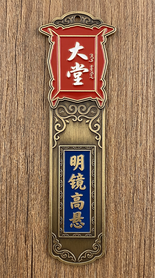重新生成排列，调整金属书签上图案和文字'大堂'、'明镜高悬'的排版布局，保持长条形状金属书签样式