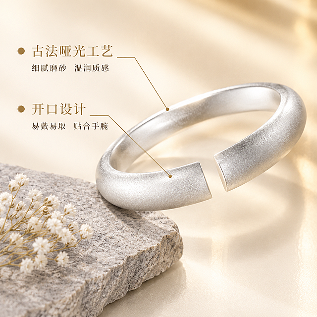 [主图-2] 古法哑光足银开口手镯核心卖点图，展示材质工艺与开口设计优势。
[统一基调] 整体风格为高级珠宝质感、精致克制、柔光微距；背景主色为奶油白配浅香槟金渐变；标题字色为深香槟金，辅助字色为暖灰色；字体为纤细优雅的文艺衬线体；无厚重色块，画面干净通透。
[画面] 手镯位于画面中央偏右，主体占比约60%，侧面视角重点展示开口处的平整切面与镯身厚度；左侧用引线标注两个核心卖点，分别指向镯身哑光表面和开口处；背景为奶油白渐变，左下角放置一块浅灰色岩板作为视觉配重，岩板上有一小束极简的白色满天星干花；手镯哑光表面颗粒细腻均匀，开口切面平整光滑无毛刺。
[光影质感] 商业珠宝摄影质感，45度侧前方主光突出哑光肌理，侧后方轮廓光勾勒镯身曲线，底部柔光补光；光影过渡自然，充分展现古法磨砂的细腻触感和金属厚重感。
[配色] 奶油白背景 + 浅香槟金点缀 + 哑光银主体 + 深香槟金文字 + 浅灰岩板，色调统一温暖。
[文字版式] 左侧上下排列两个卖点模块，每个模块含一个小圆点图标 + 卖点标题 + 简短说明；上方卖点「古法哑光工艺」配说明「细腻磨砂 温润质感」；下方卖点「开口设计」配说明「易戴易取 贴合手腕」；文字左对齐，标题字号大于说明字号，全部使用深香槟金色；文字放在左侧负空间，不遮挡手镯。
[输出要求] 1:1正方形比例，2K高清，手镯材质真实、开口结构清晰、标注引线整齐；文字清晰可读无错字；负向：变形、模糊、杂乱背景、水印、平台Logo、塑料感、划痕、手指印、文字遮挡主体。
