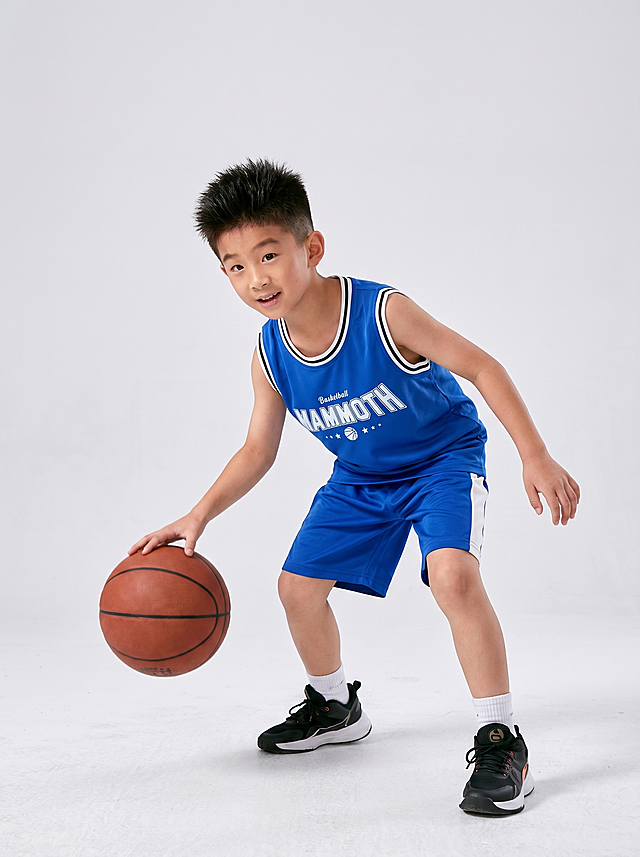 请将参考图 1 的【篮球服套装】1:1 还原其款式、颜色、材质、剪裁、图案、版型、五金细节、logo 等所有细节，穿到参考图 2 的模特身上；完全保持参考图 2 模特的身姿、面部、发型、气质、动作/姿态不变（含手部位置/朝向/重心/肩线）；模特身上参考图 1 未覆盖的部位严格保持参考图 2 原样；将画面背景替换为浅灰质感高级棚拍背景，背景干净简洁，具有高级质感。服装以参考图 1 为准，完整保留款式、蓝色、材质、剪裁、图案、版型、文字logo "Basketball MAMMOTH"等一切细节。参考图 1 未覆盖的所有部位——鞋子、袜子——严格保持参考图 2（模特图）原样，保持原有画面内容与细节一致。超高清画质，细节层次丰富，发丝、肌肤、服装纹理清晰可见，色彩还原准确，饱和度对比度适中，整体质感高级，商业摄影风格，3-4身景别，自然构图。