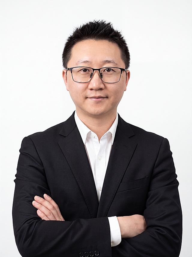 参考图中保留人物脸型、发型、年龄等特征生成职场形象照,标准焦段50mm,f/4光圈(f/2.8-f/4区间),平视视角(镜头与人物视线齐平);人物占画面70%,人物居中(居中构图),位于画面中心,为视觉聚焦点,入境范围头部及以下至臀部下方10cm(半身像);左右留少量背景空间;头部与画面顶部保留5%空间;头部发型完整,头肩比例协调,人物结构准确;发质微微柔顺，微微蓬松。身穿深黑色精纺羊毛混纺西装外套,(平驳领设计,面料呈细腻微微哑光质感);内搭白色高支精梳棉衬衫;下装深黑色精纺羊毛混纺西裤;着装正式干练;专业稳重;身形匀称,姿态端正,身体挺拔。呈双手环抱的自然姿态，肢体放松且自信;佩戴黑框眼镜，保留原有配饰;纯白色纯色背景(呈现均匀柔和质感),背景光线均匀柔和,强化色彩对比的高级感，极简干净;画质超高分辨率、细节清晰,现代精致感风格;肤质精细化处理;眼神直视镜头,目光坚定且澄澈,表情自然。嘴角上扬;肤质自然细腻,肤色健康均匀,皮肤状态清爽干净,保留真实皮肤细节｡正面柔光补光,4800K中性光,面部光比1:1.5｡中近景写实摄影,对焦清晰,面部雾面柔光,轻透裸肌感,高清保留皮肤细节｡分辨率4K,去除人物之外的所有元素。严格按照图片内容生成。画面比例3:4