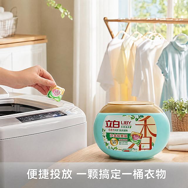 [主图-3]立白洗衣凝珠使用场景展示图，保持产品外观颜色结构与原图一致，杜绝变形色差。展示家庭日常洗护场景：干净整洁的洗衣机旁，一只手自然拿出一颗洗衣凝珠，背景是晾晒好的带着淡香氛围感的柔顺衣物，阳光透过窗户洒进来，温馨自然。商业摄影质感，光线明亮通透，真实自然家庭氛围，干净清爽。产品放置在画面右下侧主体位置，左侧展示使用动作，场景自然代入。光影：柔和自然光透过纱帘，整体明亮温暖，衣物和产品都有自然明暗层次。配色：浅米白墙面搭配浅木色地板，产品浅青蓝成为视觉焦点，绿色植物点缀，清新舒适。文字版式：底部浅灰色半透明渐变区域，文字"便捷投放 一颗搞定一桶衣物"，白色清晰字体居中，不遮挡主体。比例分辨率：1:1比例，4k分辨率，文字清晰可辨，超高清。负向提示词：变形，文字错乱，产品模糊，背景杂乱，水印，电商平台Logo。