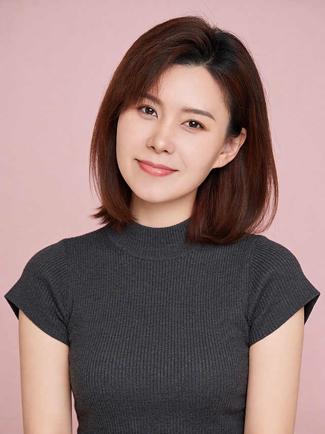 参考第一张图保留人物脸型､年龄等特征生成职场韩系肖像照,清新甜美风格的女性肖像写真,聚焦人物柔和气质,竖幅(纵向构图),50mm标准焦段,中近景(覆盖头部､肩部及部分胸部)参考第二张图人物占位和比例,人物占画面约70%,头部发型完整,人物居中,居中构图,左右留少量空间,平视视角(与人物视线平齐),深炭灰色中领修身针织短袖(袖口直角开口设计),温婉清新+柔和亲切;自然舒展正面姿态,颈部线条舒展,肩部自然下沉;嘴角轻轻微笑,视线直视镜头,整体姿态松弛无紧绷感;发质柔顺,带轻微蓬松感;伪素颜淡妆,清透奶油肌肤质(均匀白皙+通透自然光泽),水润感,质细腻,水润通透,呈现自然原生肤质.轻量眼妆提亮轮廓,淡珊瑚粉色唇妆(唇形饱满柔和);柔和布光,面部光影过渡自然,眼部带清晰眼神光,发丝边缘有轻微轮廓光,整体光比低;影棚柔光,光线均匀柔和,面部阴影极淡,肤色调清新柔和,高清细腻,呈现自然真实的清新简约氛围;零噪点降噪｡去除人物之外的所有元素,32K画质,高分辨率商业肖像画质,低噪点,色彩还原准确,低饱和柔色调滤镜,整体色调偏暖,色彩对比度低;哑光质感无缝纯色背景,颜色为浅裸粉色,表面平整｡严格按照第一张图内容生成｡