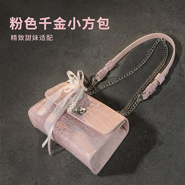 [主图-1] 粉色鳄鱼纹小方包 千金甜妹风单品首图。
[氛围风格] 精致千金氛围感，甜妹风日常场景感；
[画质] 商业摄影质感，光线柔和通透，产品清晰真实，画面干净高级。
[元素] 粉色鳄鱼纹小方包居中放置，亮面粉色鳄鱼纹纹理清晰，金属锁扣、珍珠蕾丝蝴蝶结细节完整，双链条肩带自然舒展。放在干净深灰色水泥地面上，自然摆放，光影松弛。保持包包外观（物理结构、材质质感、颜色）与输入产品图绝对一致，杜绝任何变形和色差，精细化处理。商品主体占比严格控制在65%左右，画面满屏无边框。
[光影] 自然侧向柔光，主体清晰柔和，鳄鱼纹纹理有细腻明暗过渡，金属件和珍珠有柔和高光，水泥地面有自然阴影，整体通透不灰暗。
[配色] 主色调柔粉色，深灰水泥底衬托主体，金属银色珍珠白色点缀。
[视角构图] 俯视45°斜拍，主体完整居中，景深适中，轮廓清晰不裁切。
[文字版式] 左上负空间左对齐留安全边距，大字主文案写"粉色千金小方包"，柔粉色粗体无衬线；下方小字写"精致甜妹适配"，同色系，字号缩小一半。
[比例分辨率] 1:1比例，4k分辨率，文字清晰锐利，画面超高清。
[负向提示词] 变形，文字错乱，产品图模糊，背景杂乱，水印，电商平台Logo