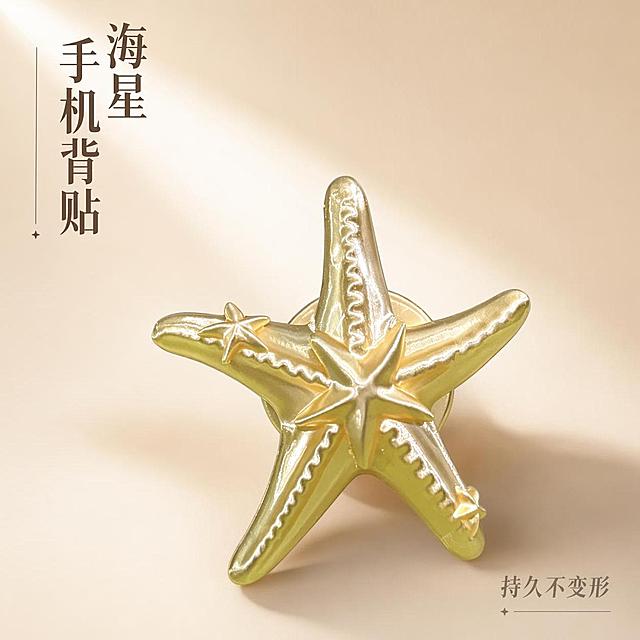 第二张产品封面图，轻奢风金色海星手机背贴主图，1:1正方形比例。本屏使用【图1】作为商品主体。
[氛围/风格] 简约时尚ins风，浅奶茶色渐变背景，突出产品设计感和金属质感
[元素布局] 海星背贴放置在画面视觉中心偏下位置，占比约65%，左上角留白，造型和颜色与输入产品图一致
[光影质感] 左上方侧光，产品边缘轮廓清晰，高光凸显金色光泽，右下角自然投影增加立体感
[配色色系] 全局底色渐变 #F5EFE4 → #E8DCC8，产品金色，深卡其文字
[视角构图] 对角构图，视觉平衡，焦点稳定
[文字版式] 左上角竖排主标题「海星手机背贴」，右下角标注核心卖点「持久不变形」，文字排版简约高级，不遮挡产品
[比例分辨率] 1:1 正方形比例，4K分辨率，高清画质，文字清晰
[负向提示词] 产品变形，颜色偏差，背景杂乱，水印，文字遮挡主体