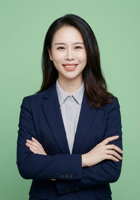 模仿参考照片风格，生成一位教师证件照，人物正面站立，双臂交叉于胸前，穿着藏青色西装外套内搭浅灰衬衫，浅绿色纯色背景，柔和均匀的商业人像布光，突出人物面部预览效果