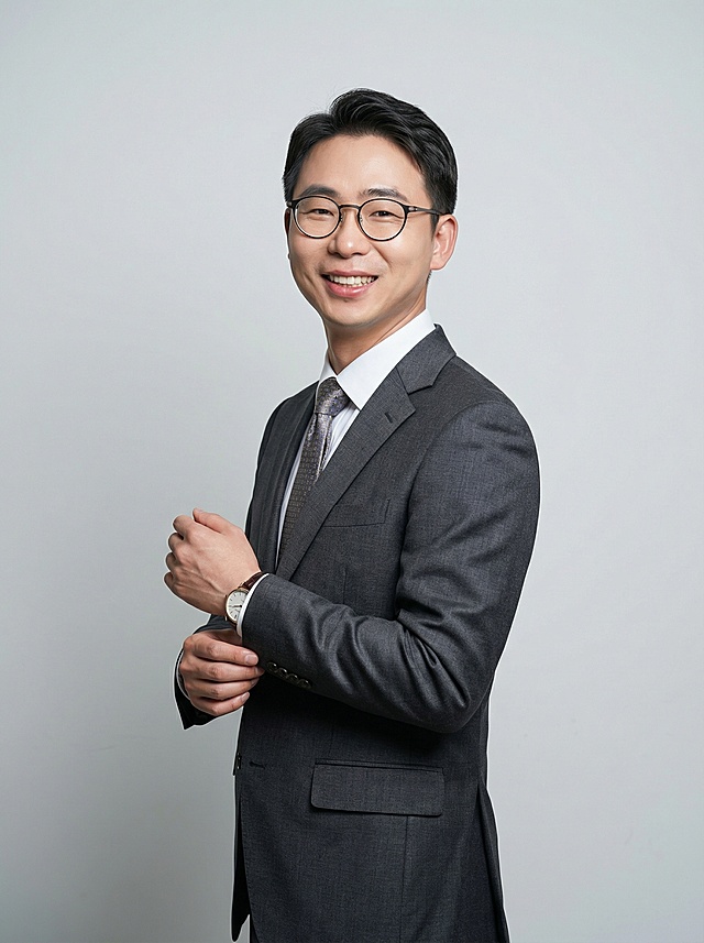 站姿：侧身+手部动作（整理袖口/抱臂）→动态不呆板！ 宣传物料：纯色背景（白/灰）要求身体微微侧向镜头，微笑看向镜头，打光商务时尚，背景浅灰偏商务，穿着为得体衬衫内搭领带和高级质感西装，同时皮肤纹理增加一些细节。脖子长一点  脸帅一点