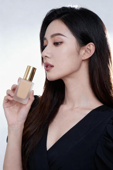 将图2的粉底液瓶子替换到图1女人的手里，保留图2的质感和造型预览效果