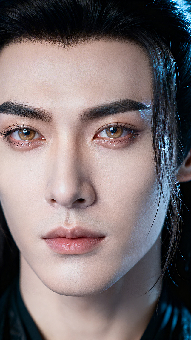 8K超高清，超写实摄影，电影级质感，竖版正脸特写，无明星特征，中式古风男倌；硬朗男性骨相，下颌线锋利，冷白皮；原生浓黑剑眉，睫毛纤长，浅棕琥珀色瞳色带湿润水光感，无浓艳妆容，清透原生质感；乌黑长发半散，鬓边垂落几缕碎发；光影柔和，无多余杂物，细节极致清晰，发丝根根分明