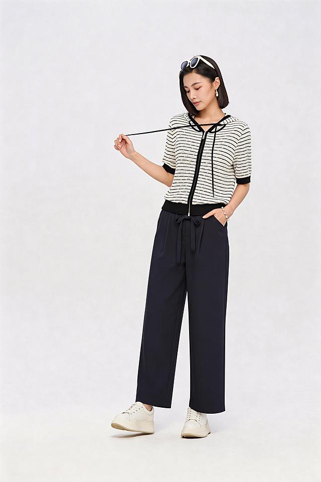 延长藏青色阔腿裤的裤脚，将裤子修改为九分裤长度，保持模特原有姿势、上衣款式颜色纹理和背景不变，裤子原有颜色和纹理保留