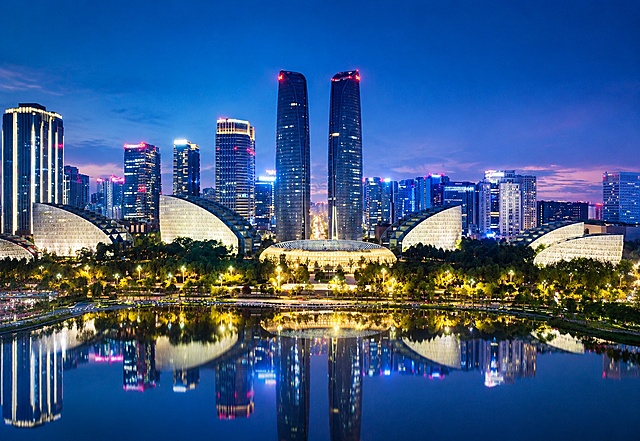 参考图片的城市夜景风格，重新生成画面内容，保持现代都市天际线、双子塔地标建筑、水域倒影、蓝调暮色氛围的整体风格