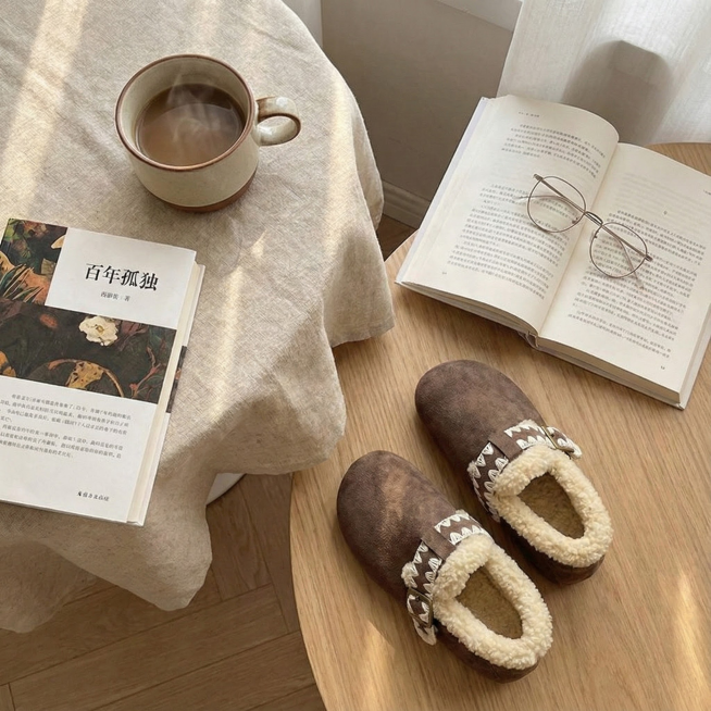 画面： 鞋子被随意但美观地放在一张铺有亚麻桌布的圆桌旁，桌上有半杯咖啡、一本翻开的书（《百年孤独》或类似文艺封面）、一副金属细边眼镜。鞋子是焦点，环境是氛围衬托。

角度： 俯拍或平视，强调“安静陪伴预览效果