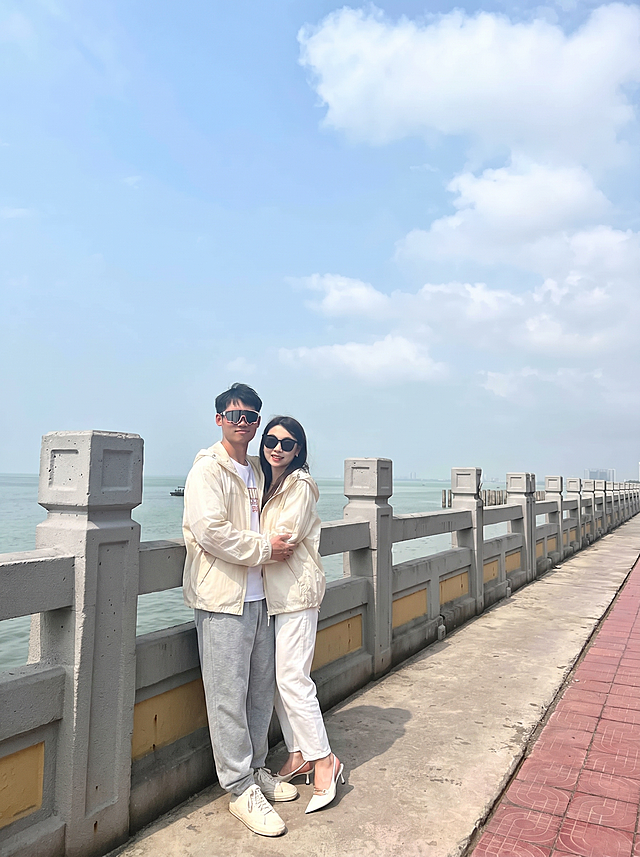 将图2的米白色连帽外套分别穿到图3这对情侣身上，男女都换上这件外套，替换掉原来的衣服，过渡自然平整，保持原来的海边护栏背景和人物拥抱姿势，图片比例3比4