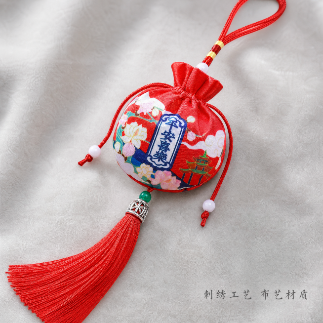 [主图-2] 国风香囊单款细节展示，氛围风格：中式雅致特写，背景为浅灰色绒布垫。画质：商业微距摄影质感，纹理清晰，光线通透，画面干净高级。元素：红色平安喜乐款国风香囊居中放置，微距特写刺绣图案和吉祥文预览效果