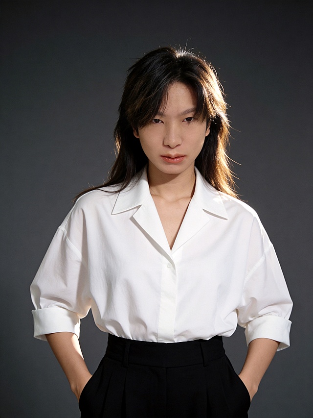 成熟知性都市精英风人像写真,简约高级,传递从容自信的女性力量;成熟知性风精英人像写真,简约高级的经典视觉基调,传递从容自信的职场气质;人物主体温和眼神直视镜头(眼波柔和,唇带浅淡微笑),(发丝微微光泽,自然垂落修饰脸型),精致裸妆(暖棕色调唇膏,清淡眼妆);环境与构图:墨灰(微微冷调)纯色哑光虚化质感背景,近景(取景覆盖头顶至臀部以上区域),三分构图:人物位于画面中心，为绝对视觉焦点,平拍视角(镜头高度与人物眼部平齐,增强亲近感);光影与色彩:柔光从前方45°右侧打光,左侧辅光补光,侧后方微微逆柔光微微打亮人物发梢与背景做区分,强度柔和,全景5500K自然光中性色温,面部光影过渡自然,突出面部轮廓立体感;色调为经典配色(白色衬衫+黑色阔腿裤),唇部暖棕为点缀色,低对比度,色彩简洁高级;细节补充:上装为平驳翻领纯棉白色极简宽松Oversize七分袖衬衫(挺括肌理,简约剪裁,袖口自然挽起),下装为黑色高腰阔腿裤(垂坠感面料,干练利落);动作姿态为双臂插于裤袋,身体呈正面面向画面人物居中为绝对视觉核心,自然站姿;肩部自然放松;氛围为高级人像质感滤镜(对比度,5,饱和度+3,柔和光影突出人物温柔气质);画质参数:超高清4K分辨率,中度锐化,细节清晰,无明显噪点,发丝､衬衫肌理纹理呈现自然真实｡