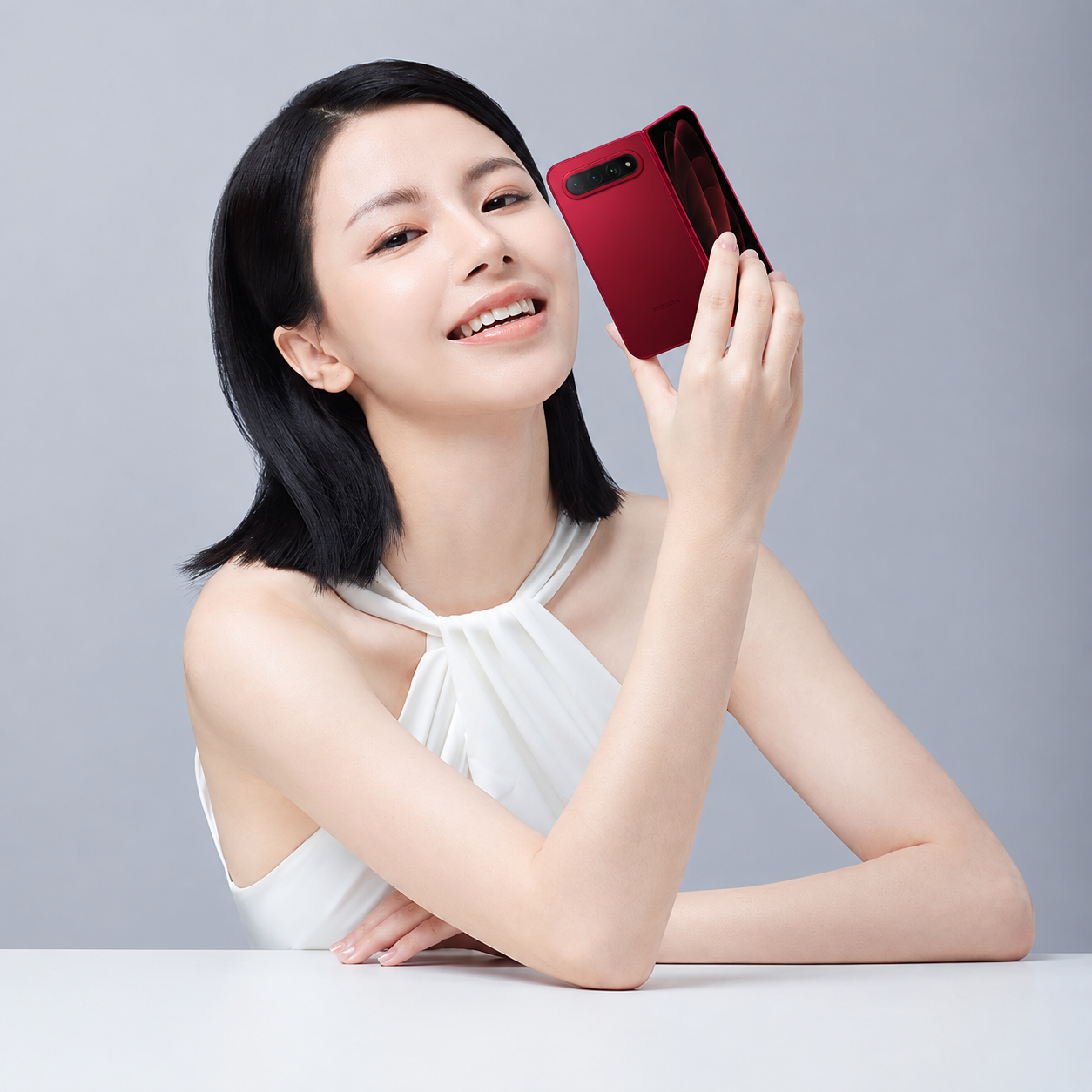 第一张图中的美女手拿第二张图中的红色小米折叠手机，保持美女的姿… - 图片创意预览