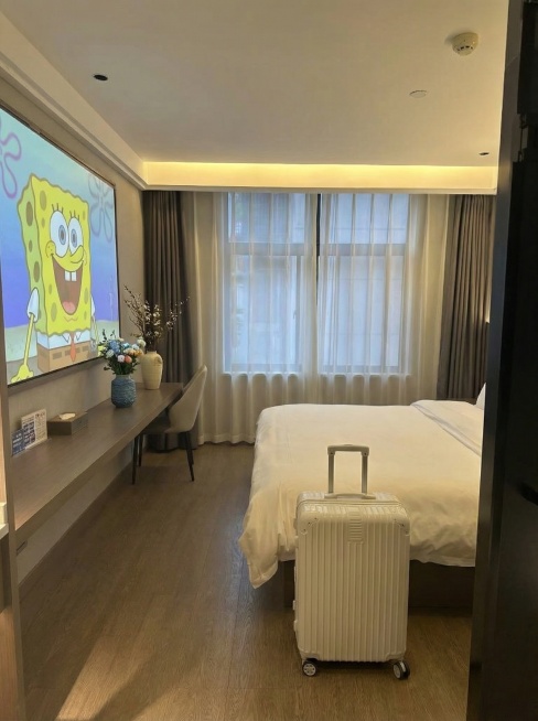 在地上添加一个白色带轮子行李箱，投影仪上添加一张海绵宝宝图片，桌子上添加两个花瓶预览效果