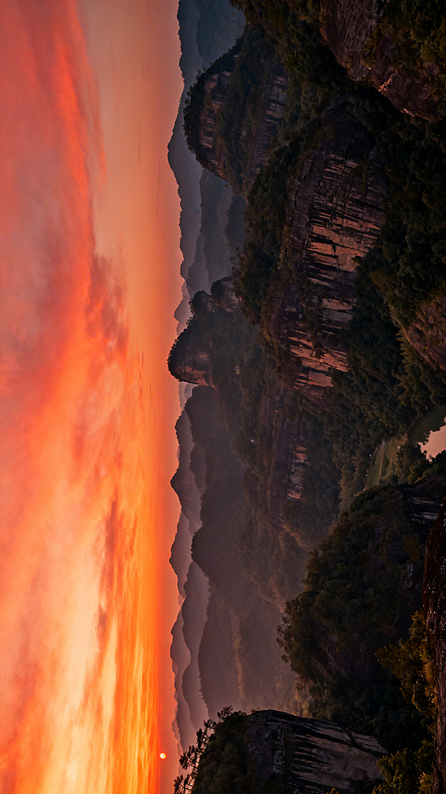 暖色调滤镜的武夷山晚霞全景图，天空橙红晚霞，山峦叠嶂，色调温暖宁静，适合作为H5封底背景