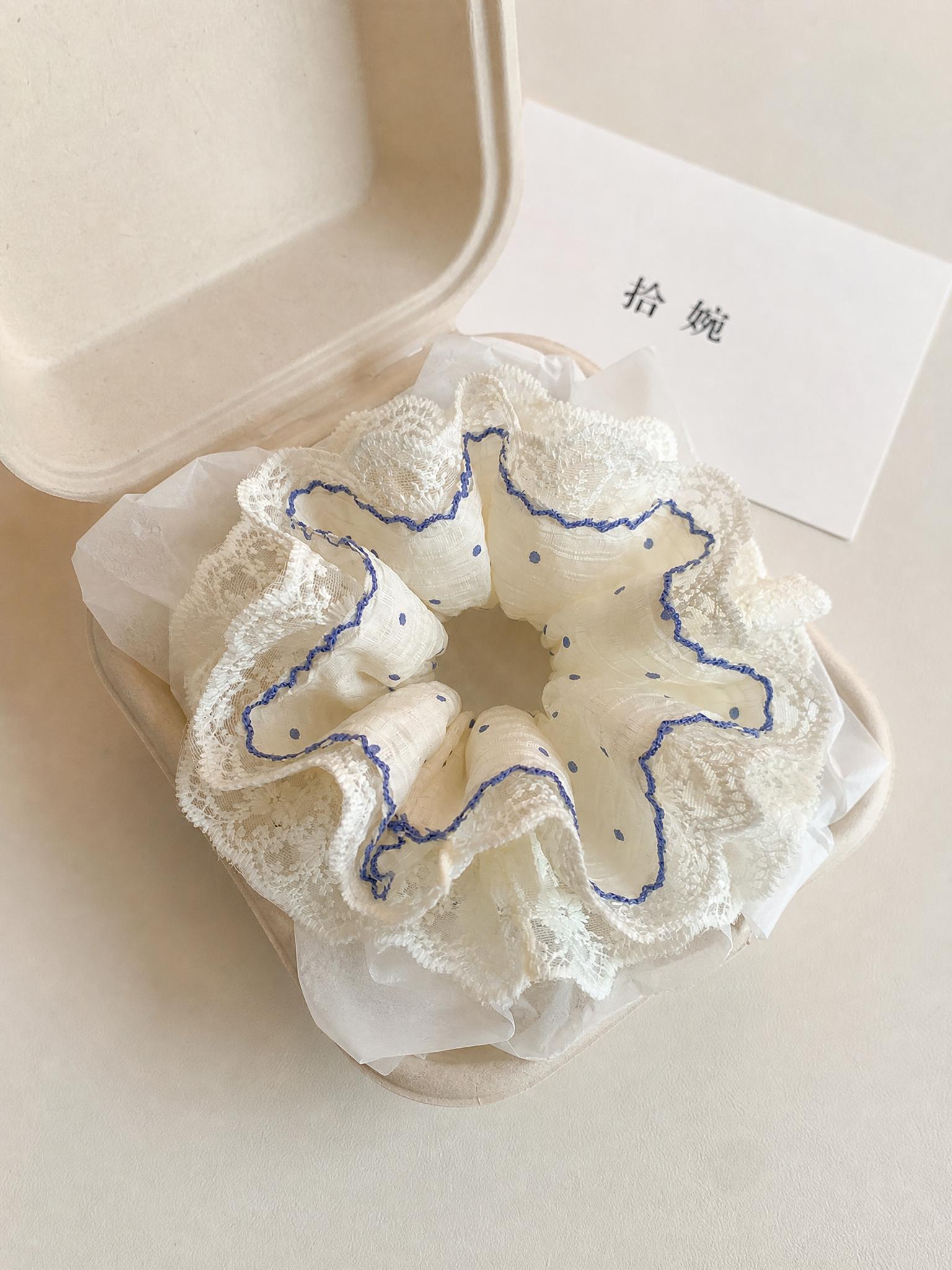 俯拍平铺静物摄影，韩系甜美蓝色波点蕾丝双层大肠发圈，放置在米黄… - 图片创意预览