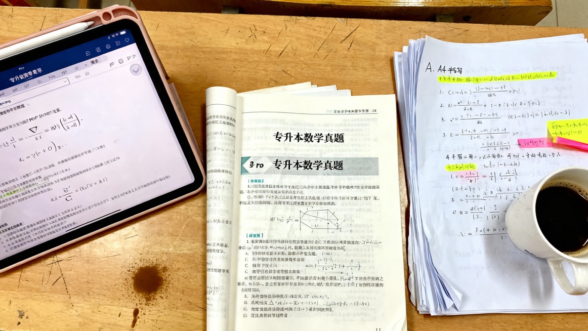 书桌一角，摊开的练习册、iPad（显示电子版公式PDF）、旁边放着打印装订好的手抄版重点公式册，上面用荧光笔画着重点。一杯提神饮品入镜，氛围专注。

AI指令：真实摄影风格，俯拍视角。一张大学生书桌，预览效果