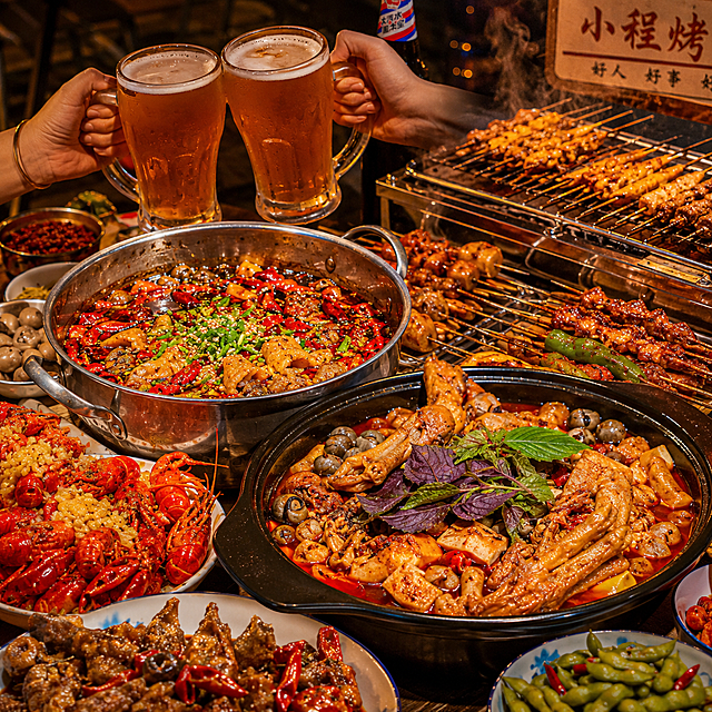 参考第一张图片的聚餐风格，重新生成菜品图，以图片中的筋头巴脑锅和螺蛳鸭脚煲作为主菜品，旁边配上正在烤的烤串，营造大排档夜宵热闹氛围，暖色调美食摄影，氛围感拉满，真实诱人