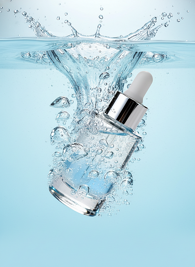 主体坠入淡蓝色背景的水中，激起水花与气泡，整体呈现出灵动、富有活力的质感，采用写实的产品摄影风格。