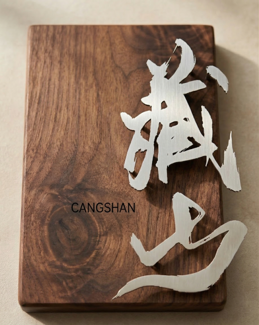 将图1中的设计稿‘藏山’和文字‘CANGSHAN’，制作成图2的工艺成品：胡桃木实木底板，金属拉丝质感的立体书法字，保留原设计排版，做写实实木挂牌，光影自然预览效果