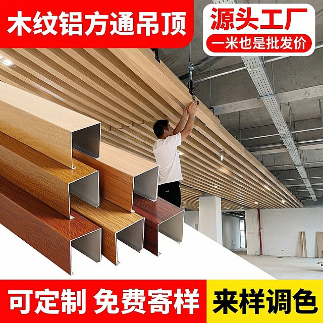 [主图 1] 木纹铝方通吊顶产品场景首图，保留原产品外观不变。氛围风格为工业简约清晰卖点型。画面左侧摆放不同颜色木纹铝方通样品，背景为大面积铝方通吊顶安装实景，一名工人正在施工安装，画面清晰开阔。配色为红白黄主色调，红色做标题底色，黄色做促销块底色，白色文字突出反差。视角为平视，景深适中。文字版式：左上角红色色块配白色粗体大标题 "木纹铝方通吊顶"，右上角白色红边胶囊标签突出核心卖点 "源头工厂 一米也是批发价"，底部红色黄色块搭配白色黑色文字展示 "可定制 免费寄样 来样调色"，字体为粗无衬线体，排版主次分明不遮挡产品主体。比例分辨率：1:1 比例，2k分辨率，保持产品与原图外观完全一致。