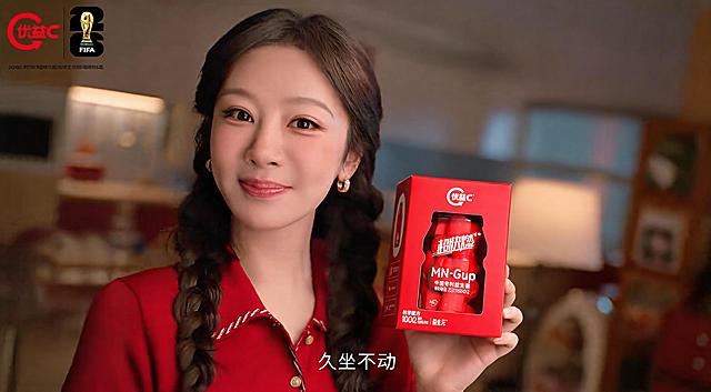 将参考图模特手中的小瓶子换成image2中的红色包装盒优益C产品，保持场景、模特姿势、光线和整体风格不变