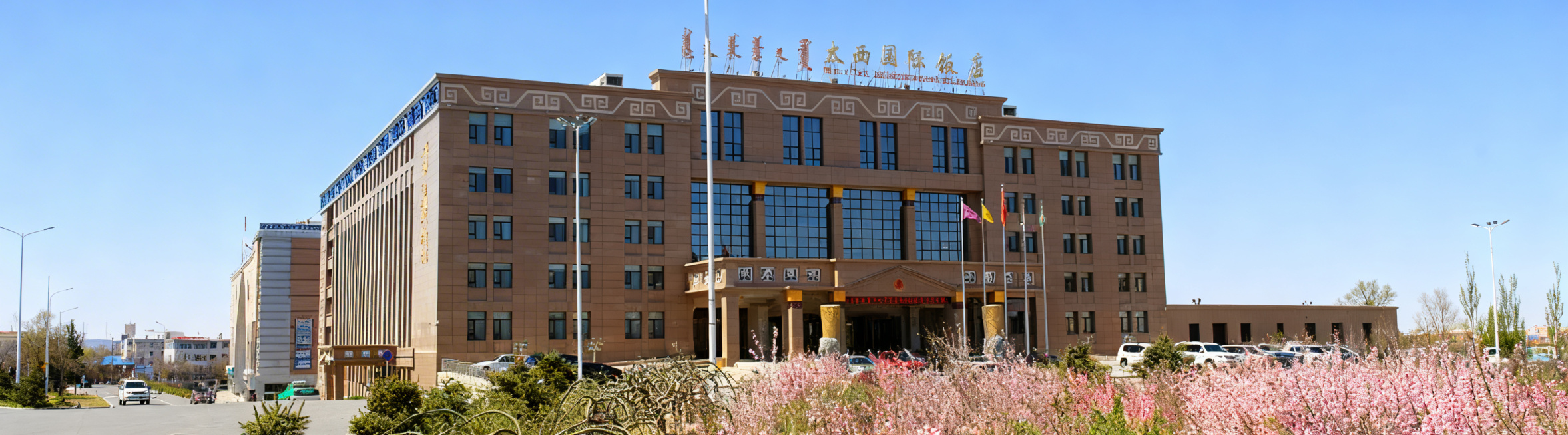 将这张太西国际饭店春日外景图片整体压缩适配到360*100像素画布，保留完整酒店建筑、顶部名称文字和前景花灌木景观，横版构图，保持原有清晰画质和晴朗蓝天实景氛围预览效果