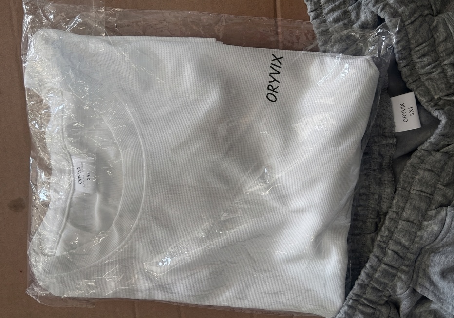 将图片上所有原有英文替换为ORYVIX，保留原有字体排版和手写风格，替换后保持包装和衣物原本的整体效果不变，保持画质清晰自然，维持原图光影和质感预览效果