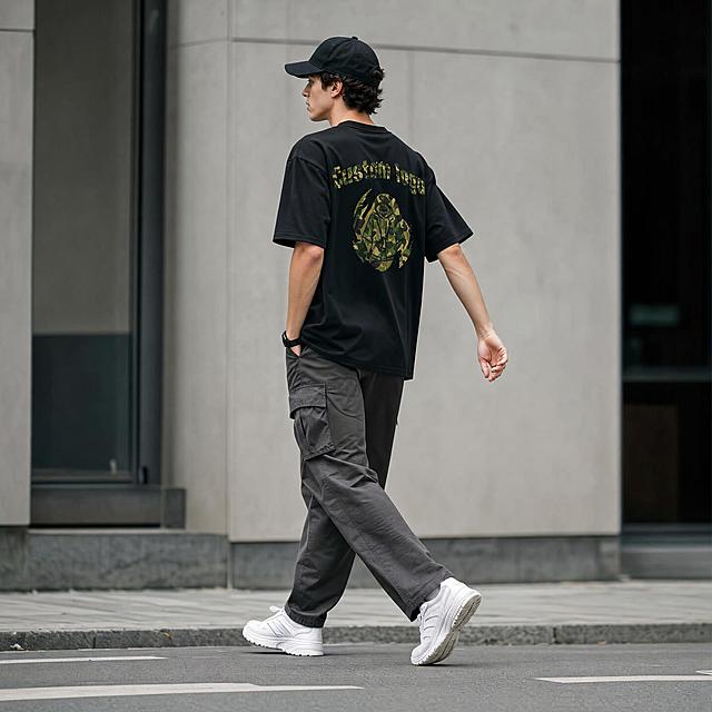 [主图-5] 黑色迷彩T恤全身穿搭场景图，欧美模特行走动态，街头潮流生活方式展示。
[统一基调] 高级街头潮流风格，极致细节，超高清8K质感，锐利对焦，无噪点，干净画面，自然抓拍时尚摄影质感。
[画面] 同一位年轻欧美男性模特，全身构图，行走动态抓拍，自然松弛有活力。模特从左向右行走，身体微侧，右手自然摆动，左手插兜，步伐轻松有街头感。模特穿着黑色迷彩图案短袖T恤，背面图案在行走中若隐若现，版型宽松随动作有自然褶皱；下装搭配深灰色工装休闲裤，脚穿白色复古运动鞋，头戴黑色棒球帽，整体穿搭完整协调，街头潮流风格强烈。背景为现代城市街头极简场景，浅灰色建筑外立面，干净的人行道，背景虚化处理，突出人物主体。画面充满生活气息和潮流氛围感。
[光影质感] 自然柔和的日间散射光，光线均匀通透，人物和服装立体感强，面料随动作产生的自然褶皱光影真实，整体画面干净高级。
[配色] 城市灰调背景，黑色T恤，迷彩绿图案，深灰裤子，白色鞋子，黑色帽子，整体冷色调高级街头感。
[文字版式] 画面无任何文字，纯图展示。
[输出要求] 1:1正方形比例，2048x2048像素，4K超清分辨率，极致锐利对焦，无噪点，画面干净，人物动态自然不僵硬，无畸形手、无穿模、无面部扭曲，无变形、无模糊、无水印、无平台Logo。