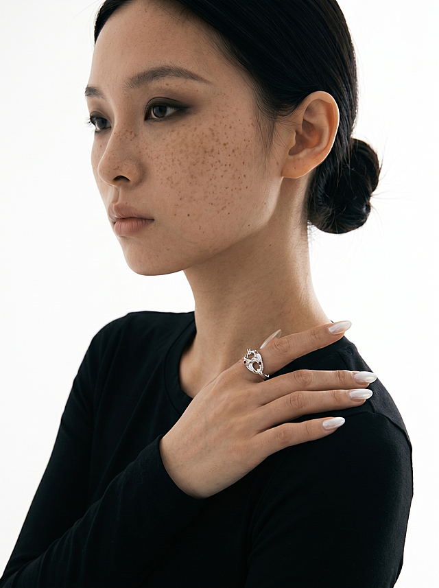 电商模特图：同一位东亚雀斑模特，黑色低盘发，黑色上衣，小烟熏眼妆，纯白背景；姿势2：侧身45度，手自然搭在肩部，中指佩戴银色链节红宝石戒指，手指舒展；柔和左前方柔光，突出戒指细节；画面比例3:4