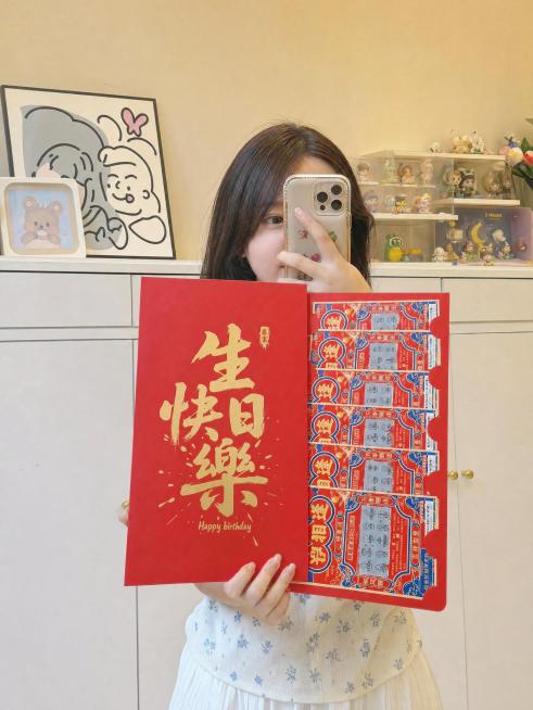 画面中心为穿着夏装的女性，以对镜自拍的姿势站在全身镜前，镜头只拍到上半身：一只手举着手机挡住半张脸，另一只手自然拿着图片中的刮刮乐红包，红包和刮刮乐很大，红包和刮刮乐挡完上半身，绝不改变红包样式，大小预览效果