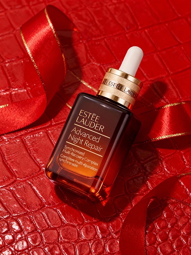 奢华高端商业摄影风格，浓郁高级的调性，画面整体采用红金高对比奢华色系配色，暖调浓郁的光泽光影，低饱和度；采用平视偏轻微俯视视角；场景为红色鳄鱼纹肌理背景，搭配印有红色金边亮面丝带装饰；主体轻微倾斜状态放置在暗红色鳄鱼纹肌理背景之上；暖调浓郁布光凸显主体光泽，营造高端奢华的品牌氛围